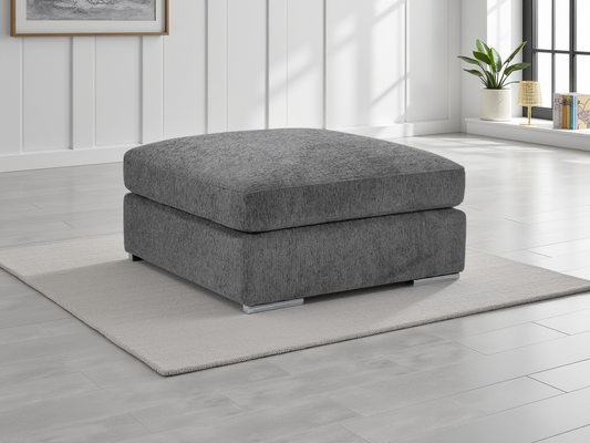 Gray ottoman in a room with light wood flooring and a window in the background.