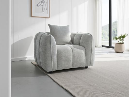 Gray armchair in a modern living room with a white wall and large window.