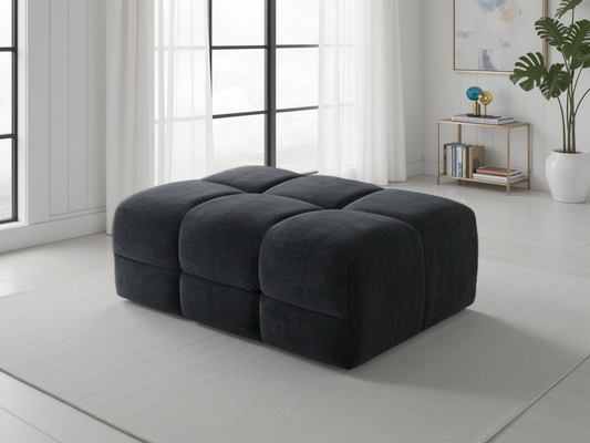 Dark black ottoman in a modern living room with large windows and minimal decor.
