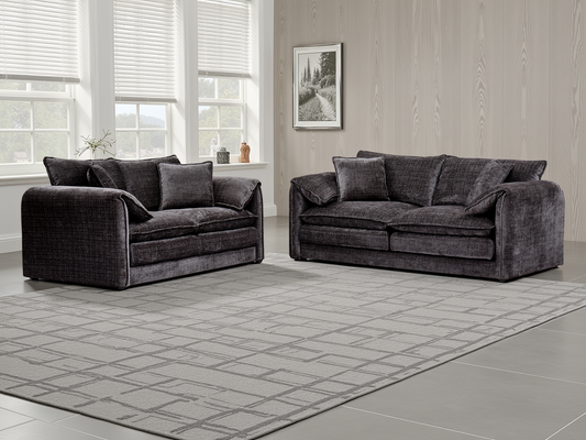 Black sofa set in a room with large windows and a framed picture on the wall.