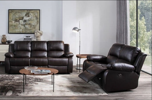 A dark brown leather recliner chair with the footrest extended, shown in a modern living room setting next to a matching leather sofa, a round coffee table, and a floor lamp.