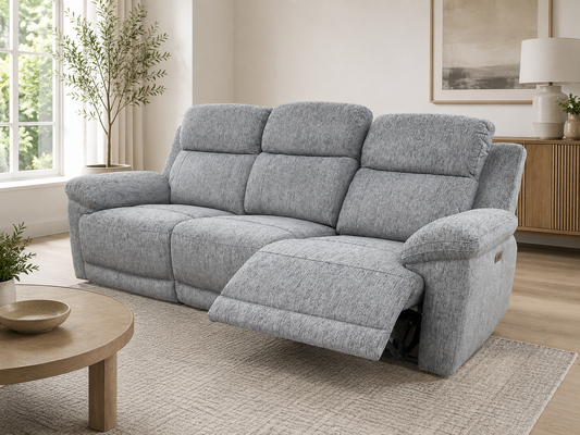 A three-seat recliner sofa in light gray textured fabric, shown with the right armrest extended in a bright, modern living room.
