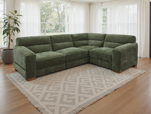 Green sectional sofa in a living room with large windows and a patterned rug.