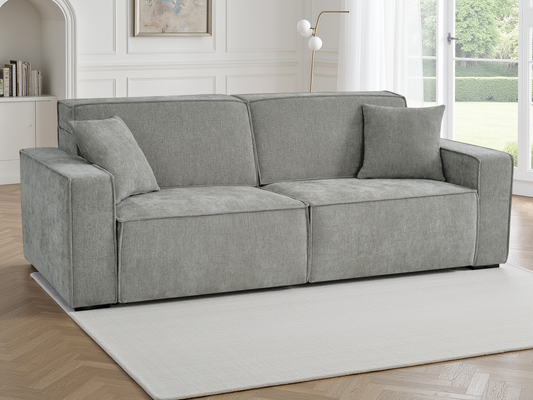 A light gray upholstered loveseat sofa with two matching throw pillows, shown in a bright, modern living room.