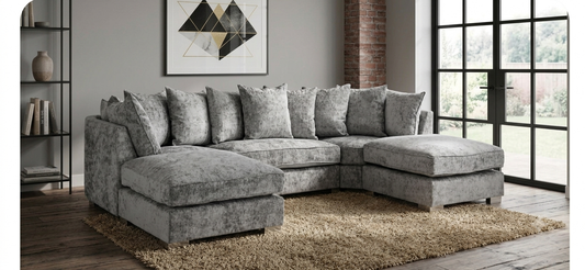 A gray upholstered sectional sofa with multiple matching throw pillows, shown in a staged living room.