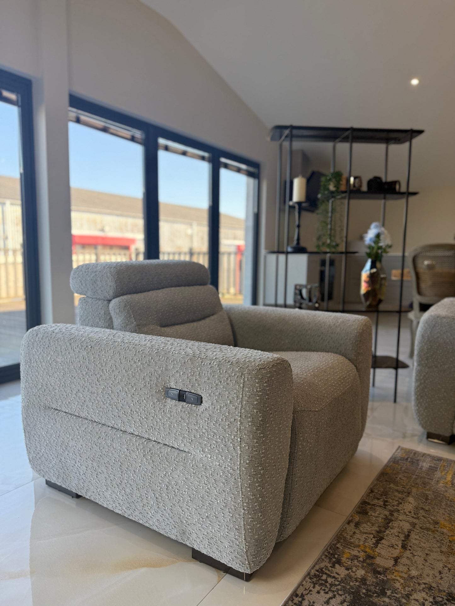 Gray armchair in a modern living room with large windows.
