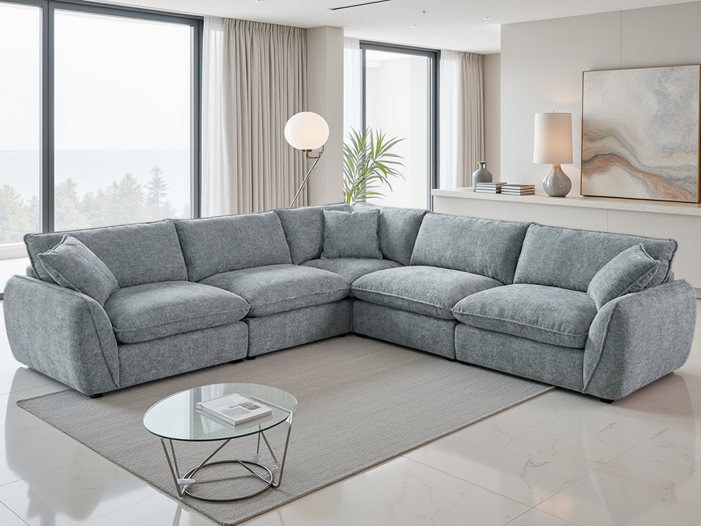 Gray sectional sofa in a modern living room with a glass coffee table and large windows.