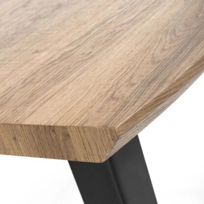 Close-up of a light brown wood tabletop with visible grain and a black metal table leg against a white background.