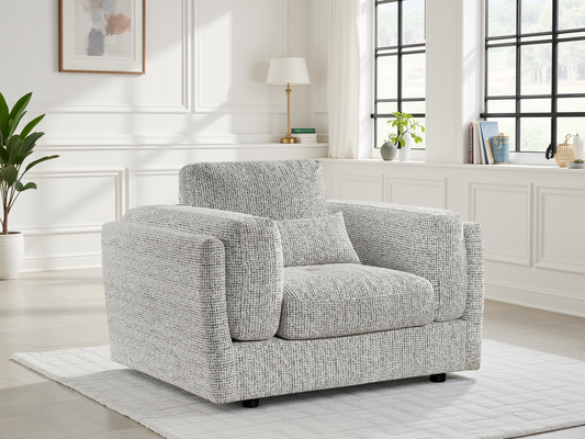 Gray armchair in a bright living room with white walls and large windows.