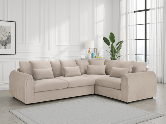 Beige sectional sofa in a living room with white walls and large windows.