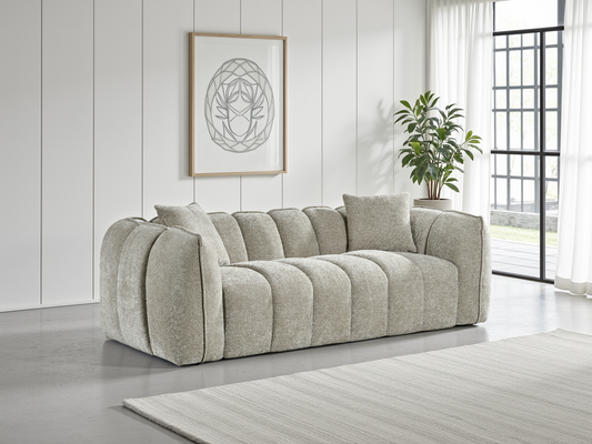 Gray sofa in a living room with a plant and framed artwork on the wall.