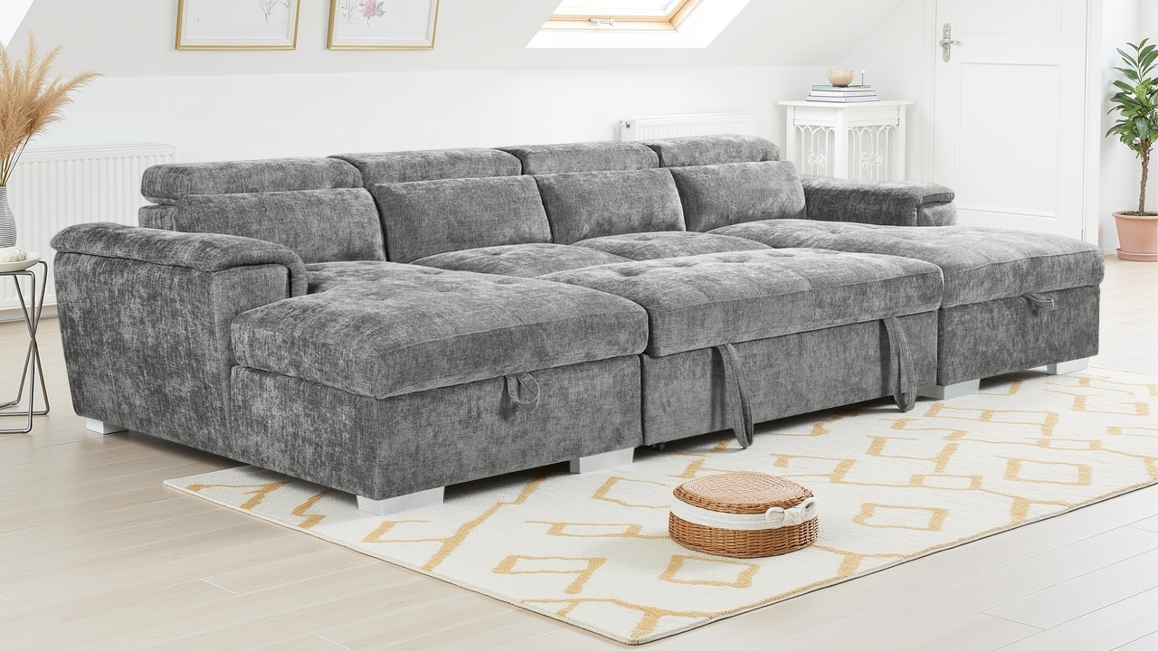 Gray sectional sofa in a living room setting with a rug and small table.