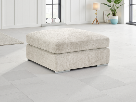 Beige ottoman in a modern living room setting with white walls and a plant.