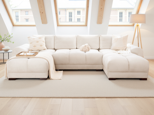Beige sectional sofa in a bright living room with large windows.