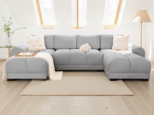 Gray sectional sofa in a bright living room with large windows.
