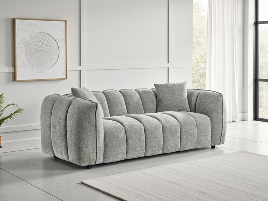 Gray sofa in a room with a large window and framed artwork on the wall.