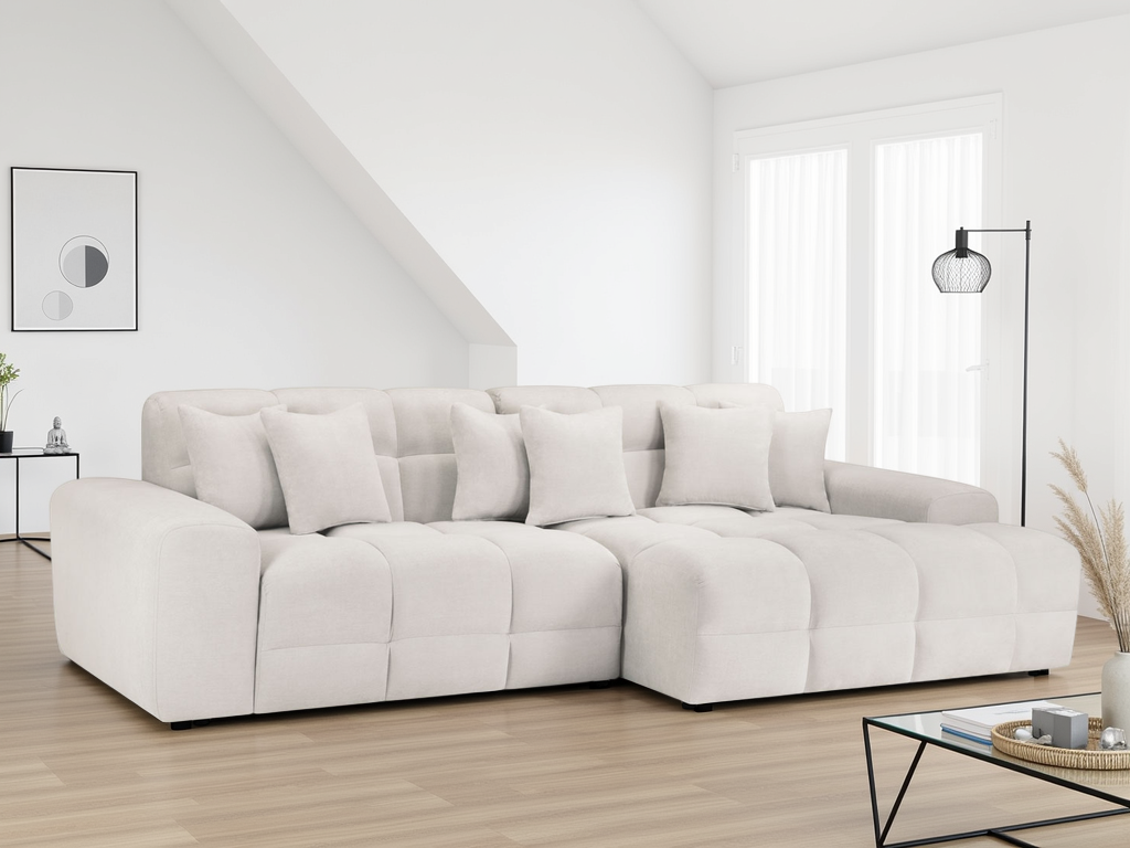 White sectional sofa in a modern living room with wooden floor and large windows.