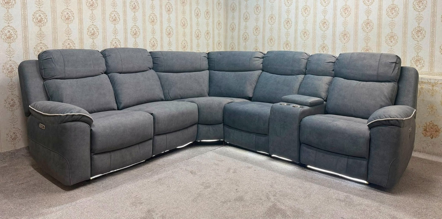 A gray fabric sectional sofa with multiple plush seat and back cushions, shown in a room with patterned wallpaper and carpet.
