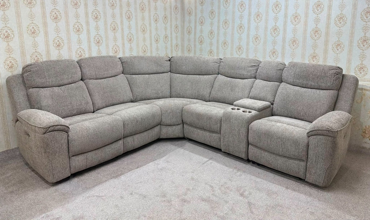 A light gray upholstered sectional sofa with recliner cushions and a center console, shown in a room with patterned wallpaper and a light rug.