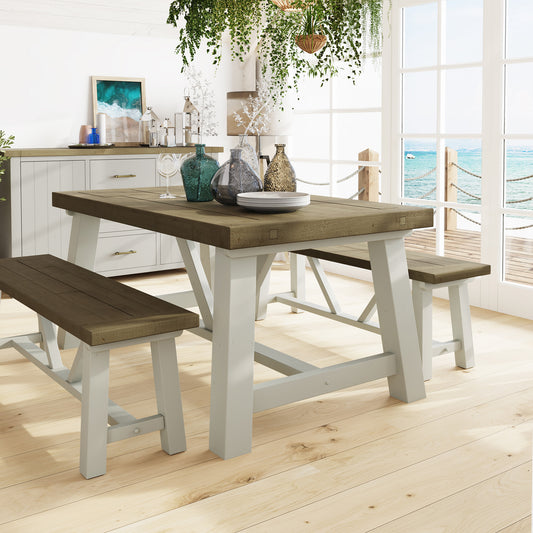1.6m Dining table with benches in a bright room with large windows overlooking water.
