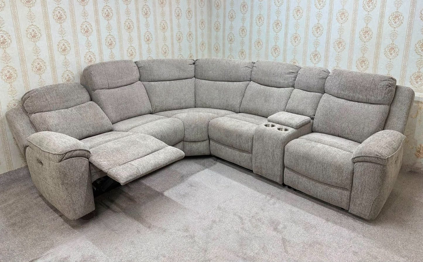 A light gray upholstered sectional sofa with a recliner section on the left with the footrest extended, a center console with cup holders, and a right-facing recliner seat, shown in a room with patterned wallpaper and a gray carpet.