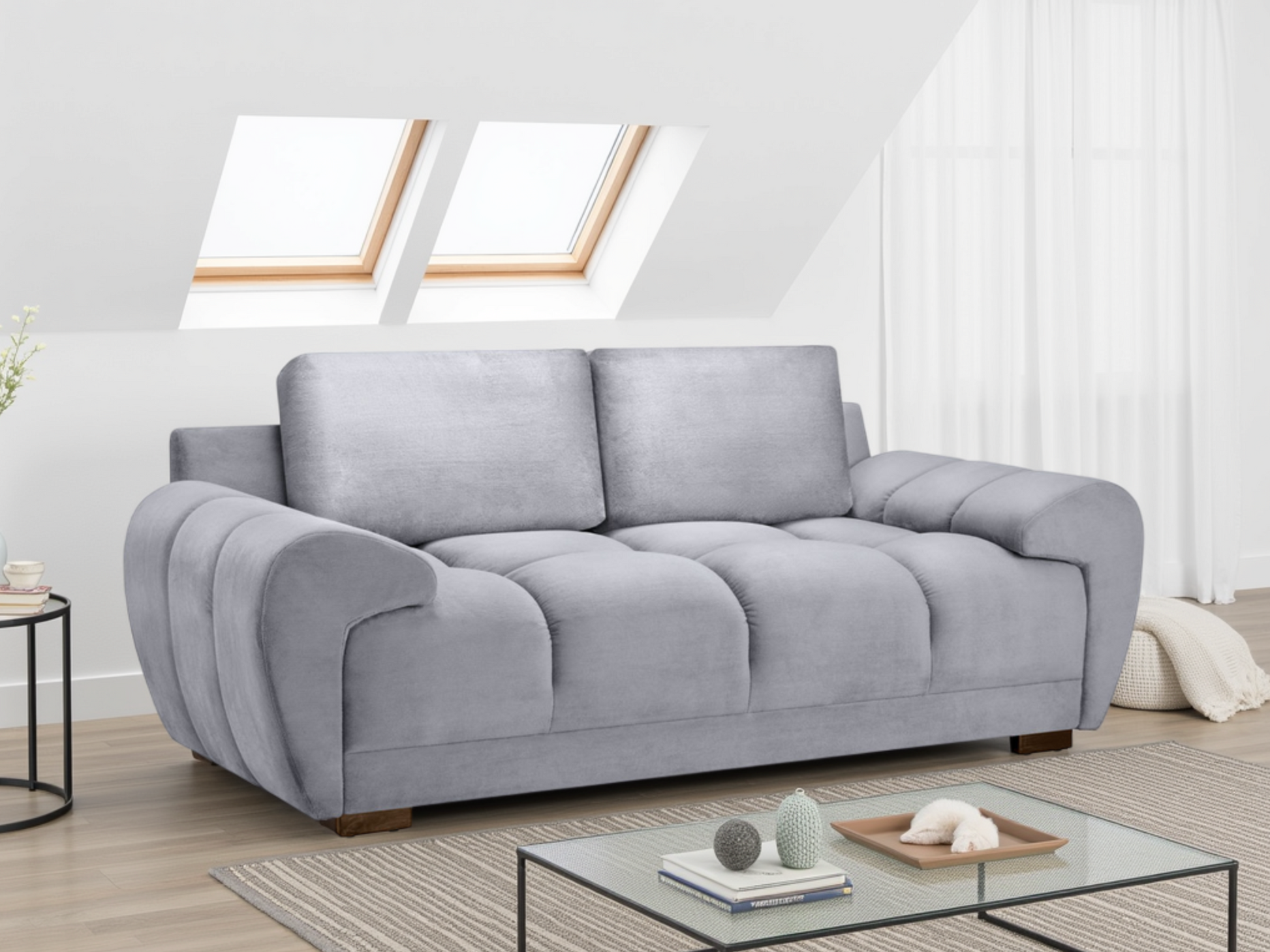 Gray sofa in a modern living room with a glass coffee table and decorative items.