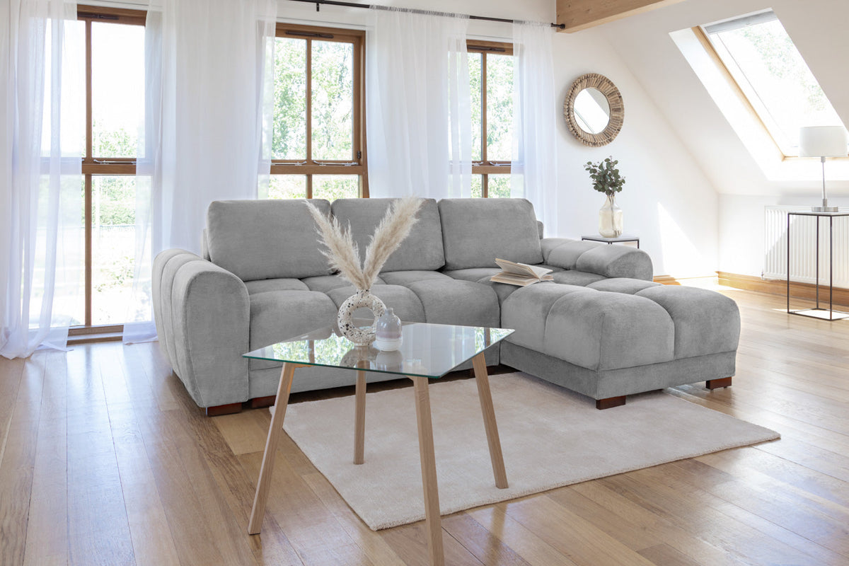 Gray sectional sofa in a modern living room with large windows and wooden floor.