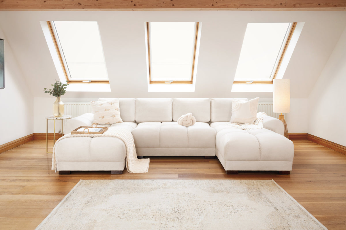 Modern living room with a white sectional sofa, wooden floor, and skylights.