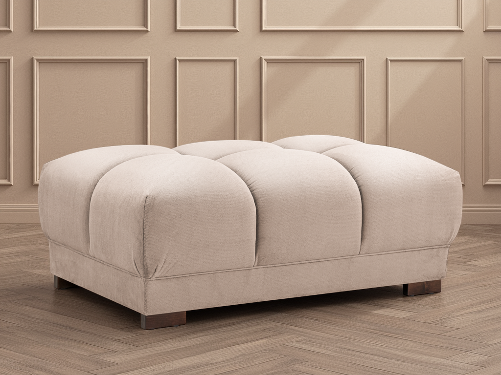Beige ottoman with tufted design on a wooden floor with panelled walls.