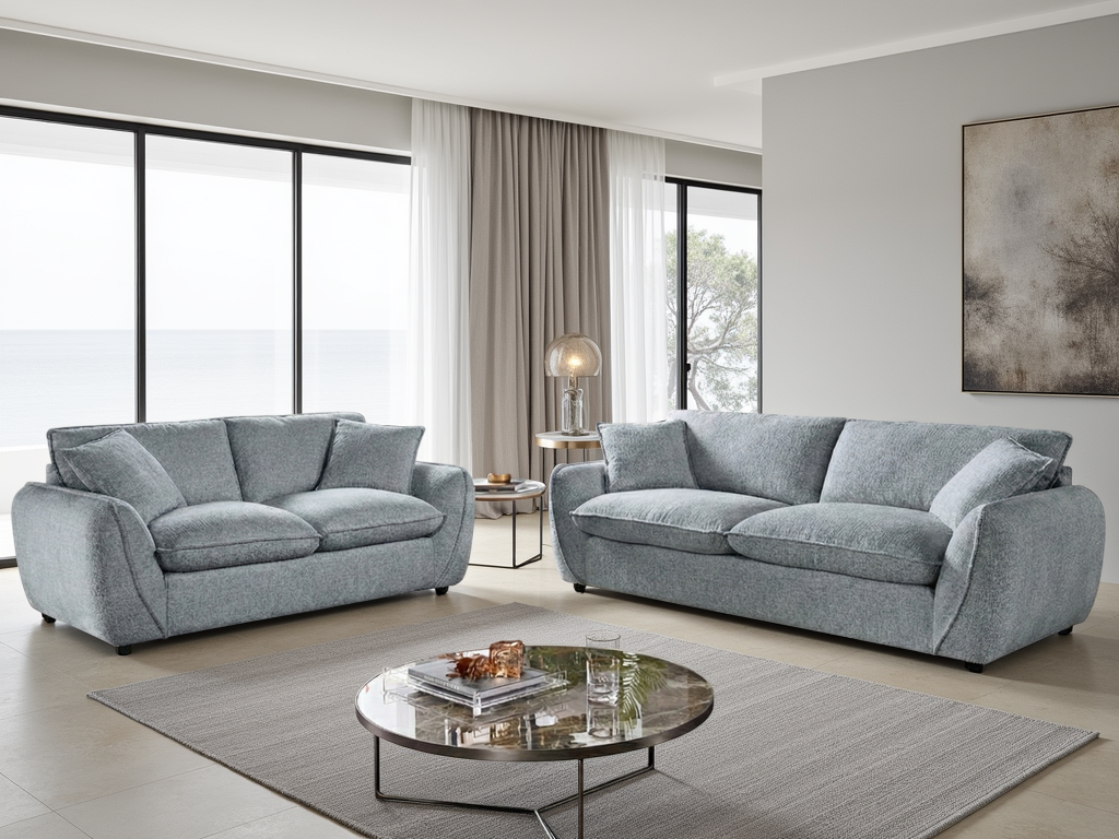 Gray sofa set in a modern living room with large windows and a round coffee table.
