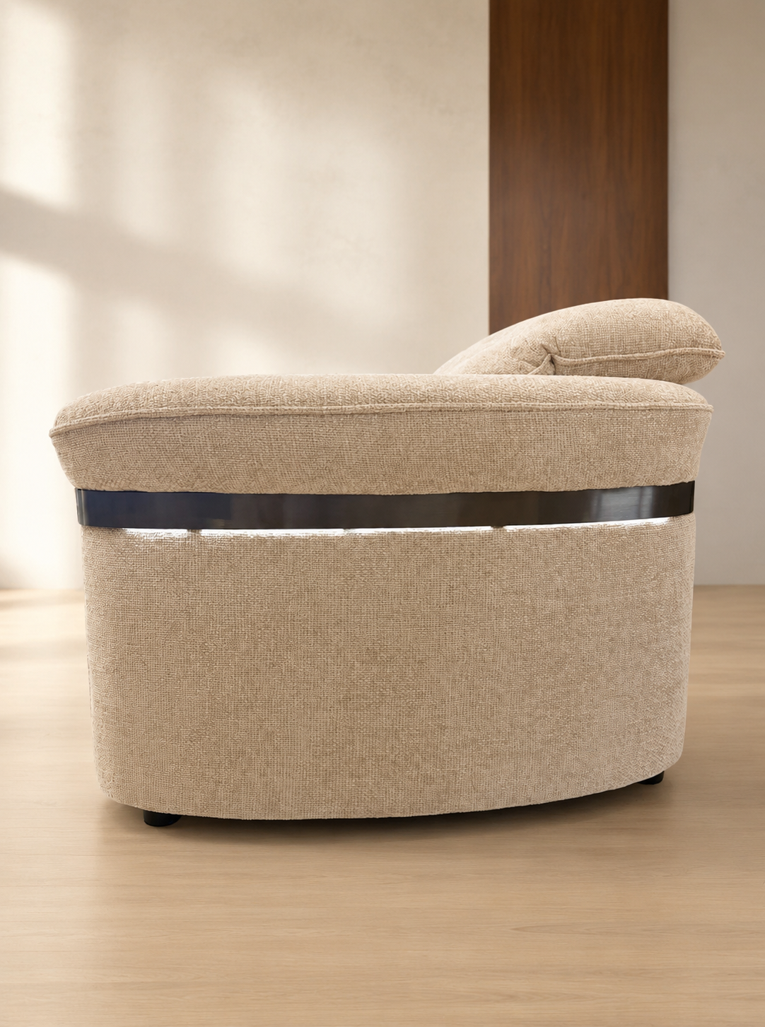 A modern curved upholstered armchair in a warm beige fabric, featuring a dark horizontal accent stripe around the middle.