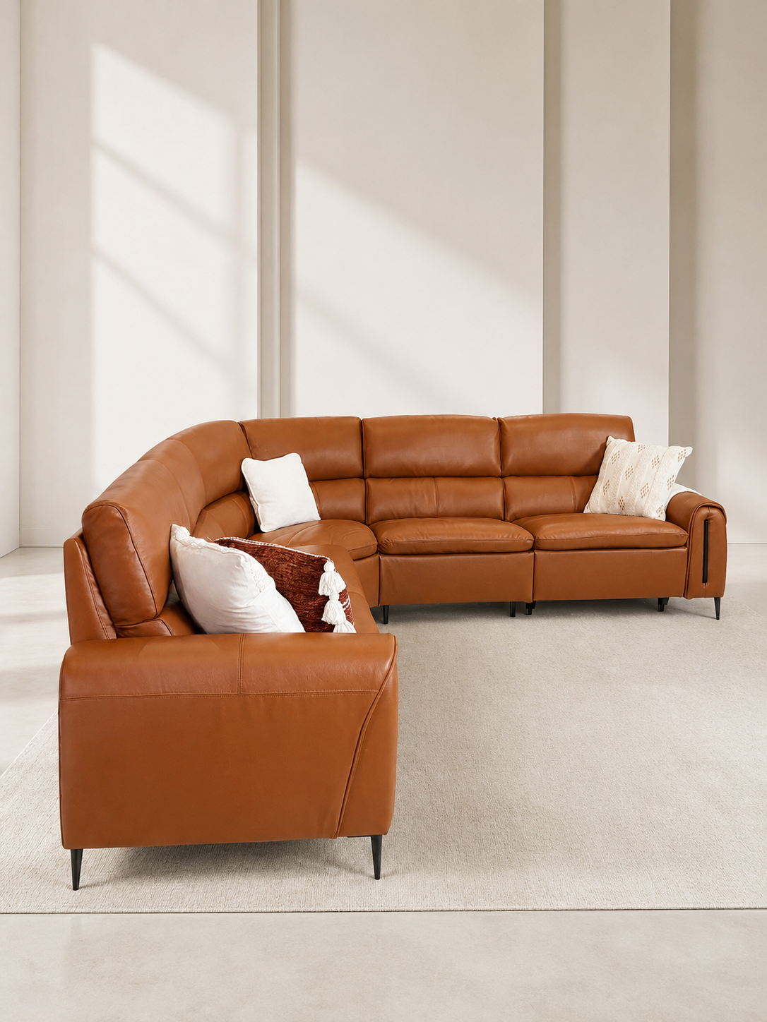 A warm cognac brown leather sectional sofa with a left-facing chaise lounge, sunlit living room.