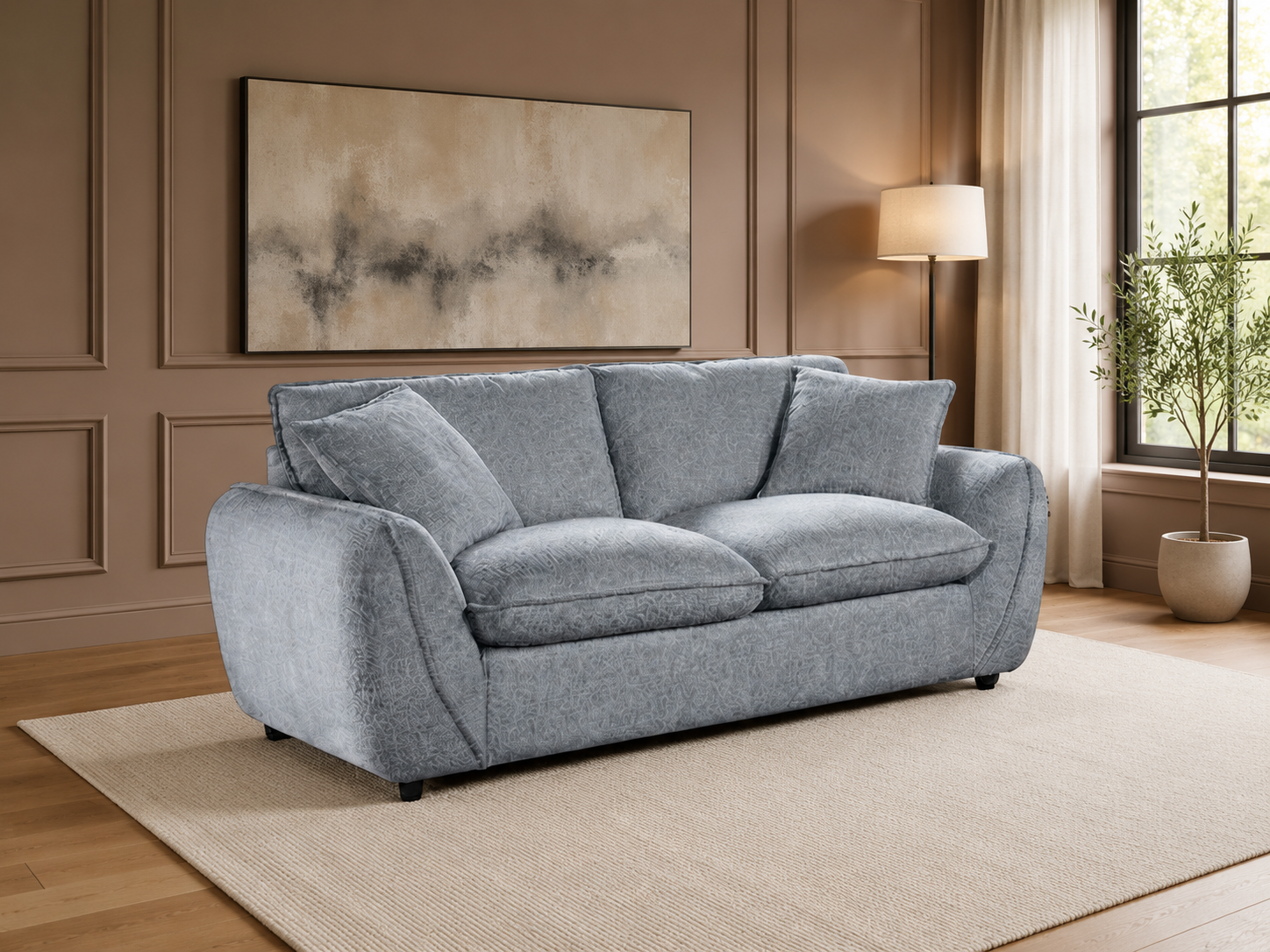 A light gray upholstered loveseat with three back cushions and two matching throw pillows, shown in a styled living room with wood paneling, a rug, a floor lamp, and a window.