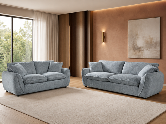 A modern living room featuring two light grey upholstered sofas, one loveseat and one three-seater.