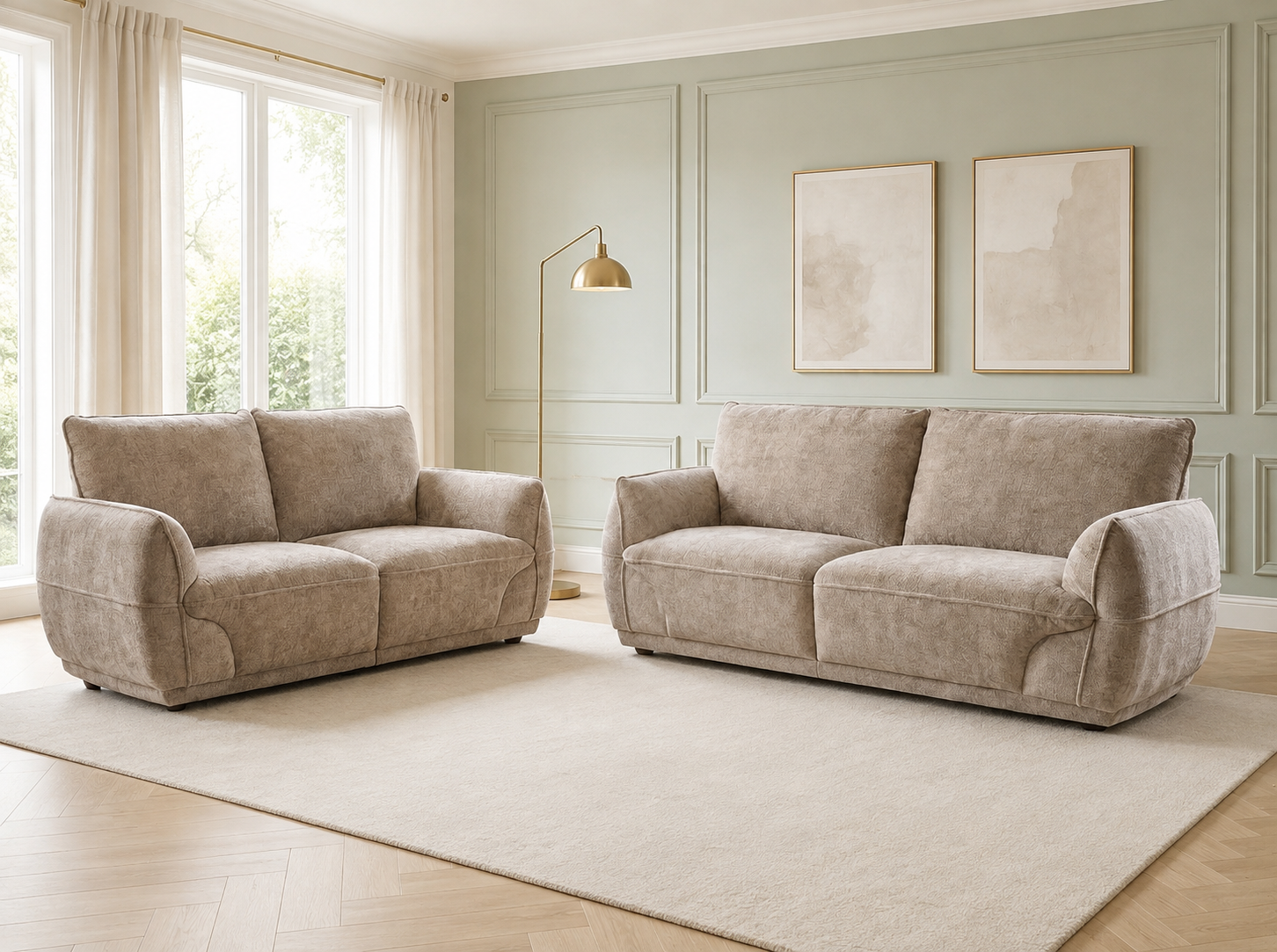 Two upholstered loveseats in a matching light beige fabric, shown in a styled living room with pale green paneled walls, a large cream rug, wood flooring, a floor lamp, and framed wall art.