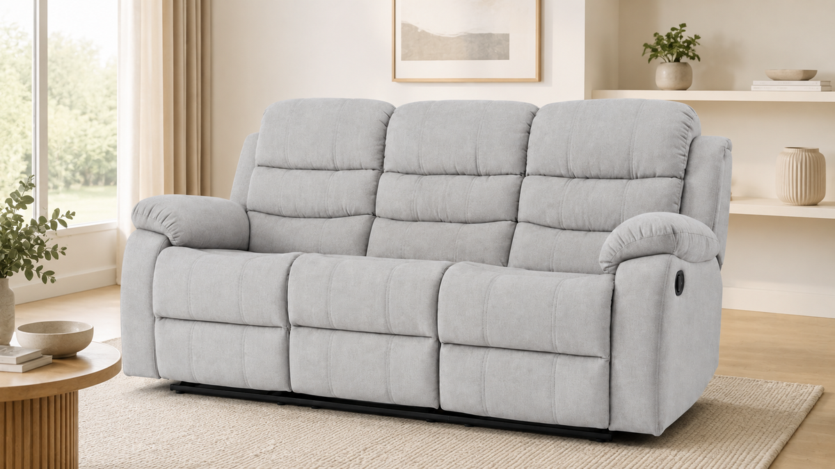 A gray three-seat reclining loveseat sofa with padded segmented backrests and armrests, shown in a bright modern living room setting.