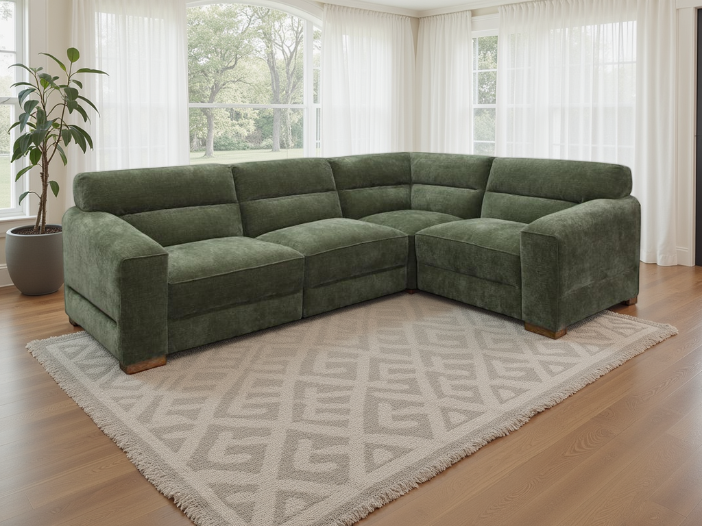 Green sectional sofa in a living room with large windows and a patterned rug.