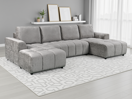 Gray sectional sofa in a living room setting with a rug and decor items.