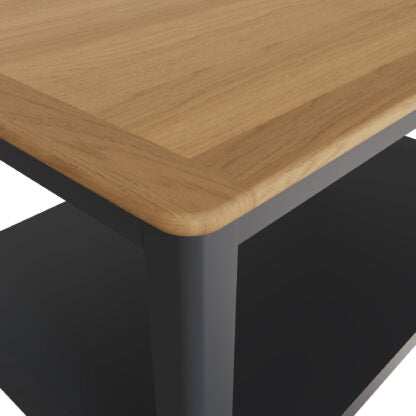 Close-up of a wooden table corner with a light oak tabletop and dark gray metal legs and shelf.