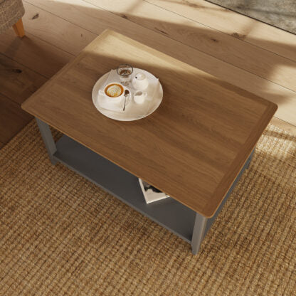 Wooden coffee table with a cup of coffee and saucer on a textured floor.