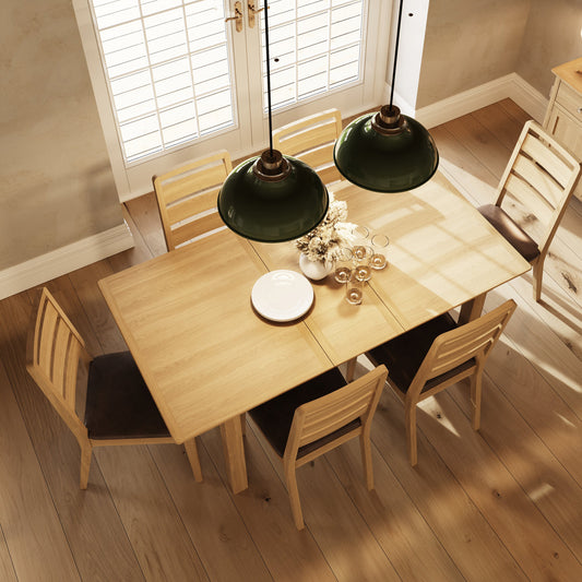 Dining room with wooden table and chairs under green pendant lights.