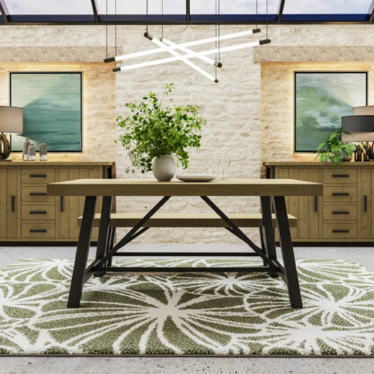Dining area with a wooden table and benches on a patterned rug, against a stone wall.