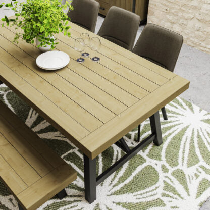Wooden dining table with chairs and a plant on a patterned rug