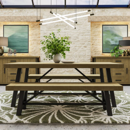 A rustic dining table with matching benches in a warm wood finish and black metal legs, styled in a modern dining room setting with a patterned rug, sideboards, and wall art.