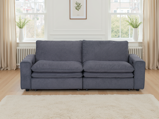 Gray sofa in a living room with large windows and light decor