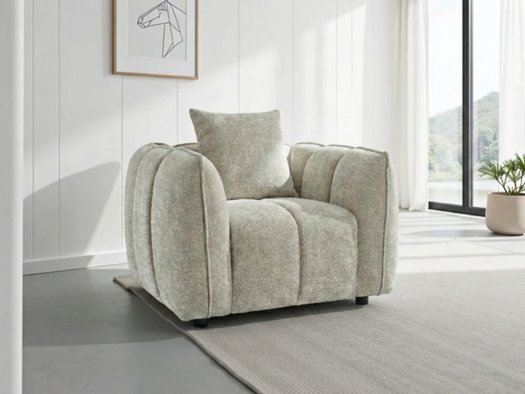 Gray armchair in a modern living room with large windows and minimal decor.