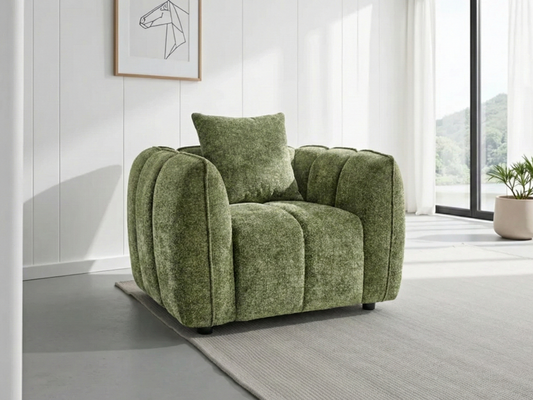 Green armchair with a pillow in a modern room with large windows.