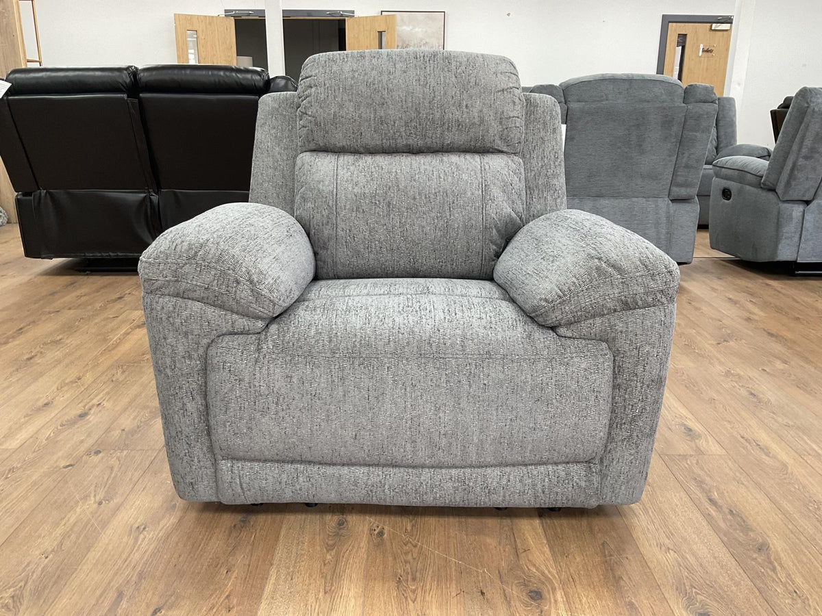 Gray recliner chair in a showroom setting with other furniture in the background.