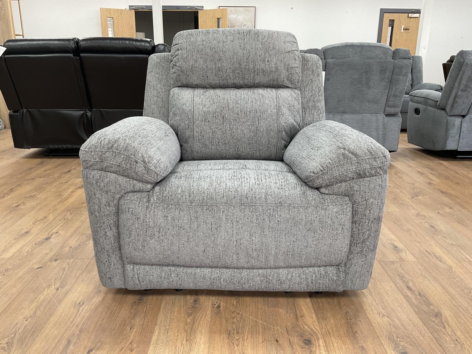 Gray recliner chair in a showroom setting with other furniture in the background.