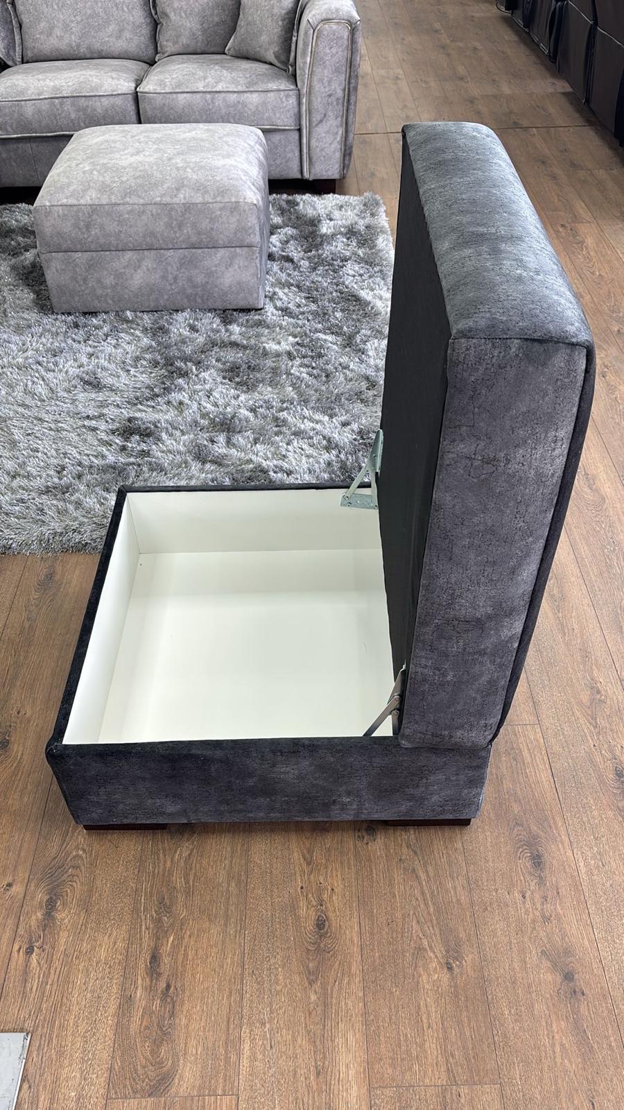 Black upholstered storage ottoman with a mirror on a wooden floor.